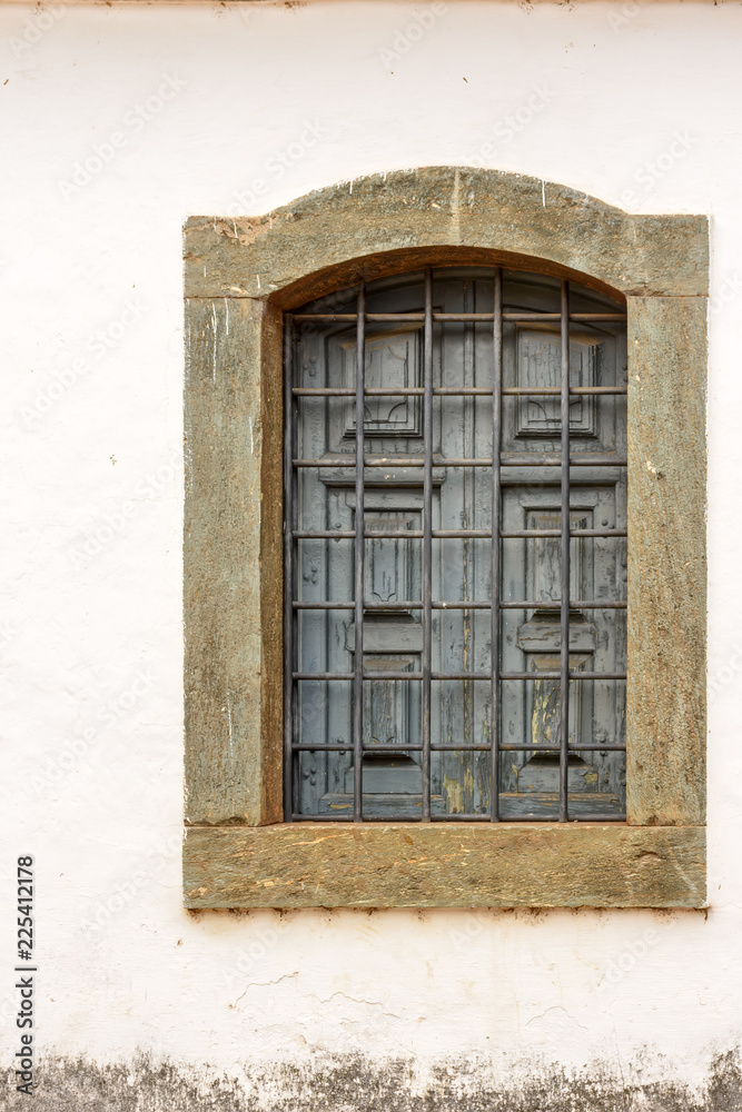 Old church window made of wood in colonial style with frame in stone in Sabara city, Minas Grerais, Brazil