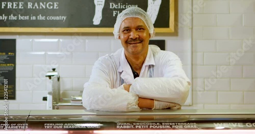 Smiling butcher standing in shop 4k photo