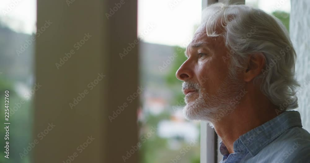 Upset senior man looking through window 4k