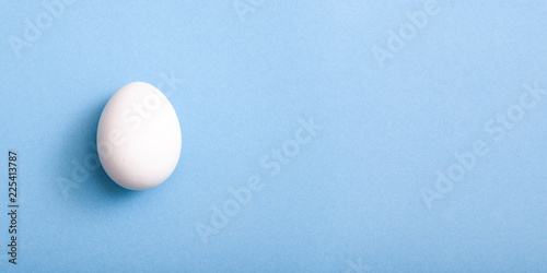 White egg on blue background with copy space