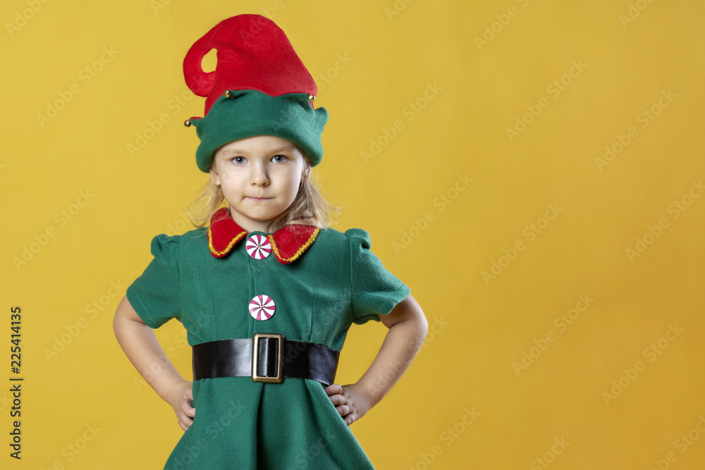 Φωτογραφία A little girl in the costume of a Christmas elf rests her hands on her hips