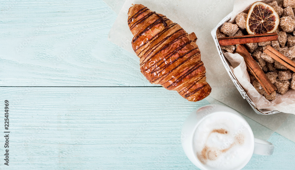 Delicious breakfast with fresh croissant and coffee latte on blue wooden background, copy space Delicious breakfast with fresh croissant and coffee latte on blue wooden background, copy space