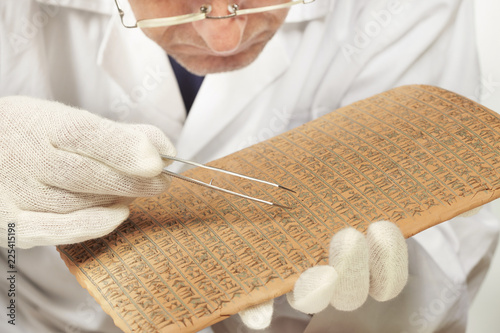 Scientist exploring ancient type of Akkad empire style cuneiform with tweezers photo