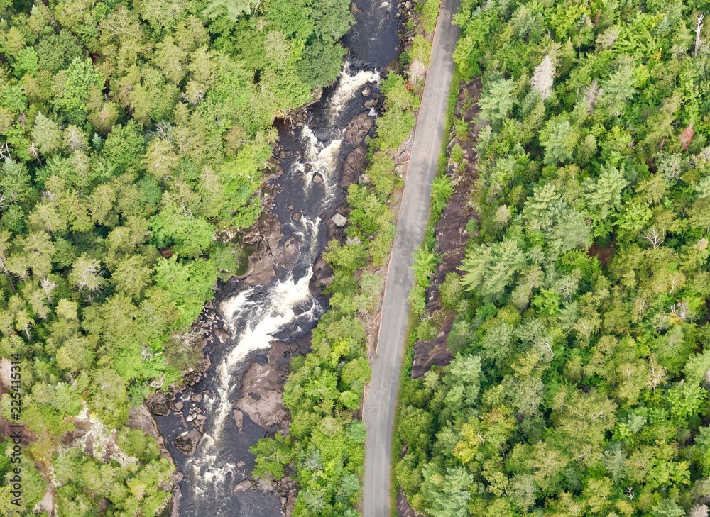 Aerial view of rapids next to a bike path running through the forest.