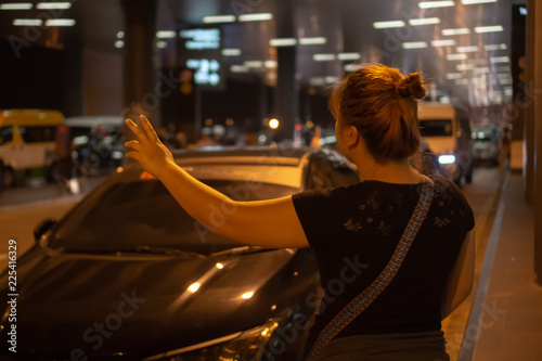 Woman hailing for cab at night in an airport.