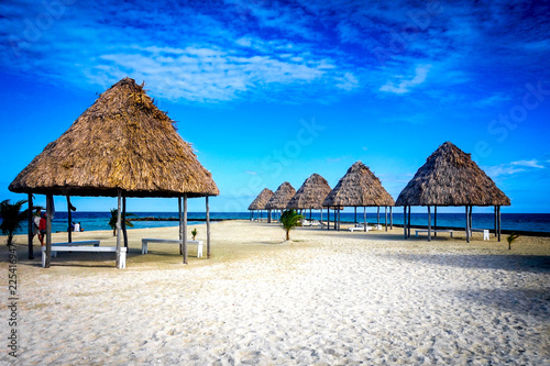 Thatched palapas on the golden sand of the tiny island of Rendezvous Caye in the Belize Barrier Reef, off the coast of Belize, Central America