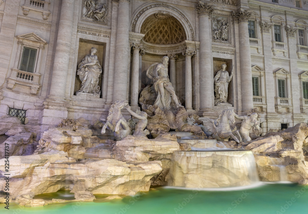 Close up of the Trevi fountain (fontana di trei) in Rome at night. The statues ares above the turquoise water.