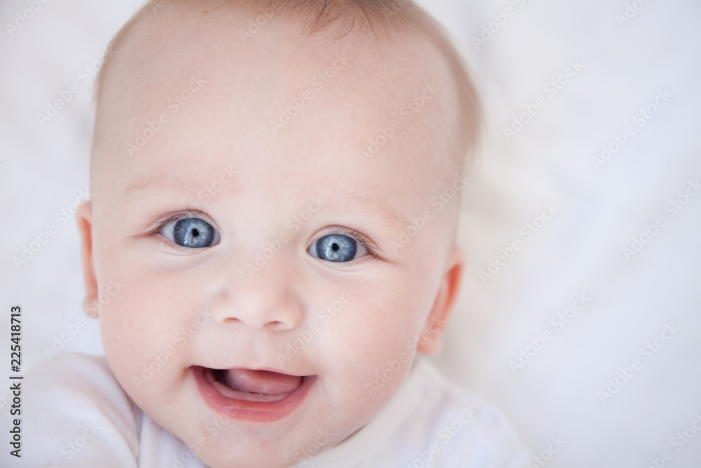 portrait of happy smiling child lies on his back on a white sheet portrait of happy smiling child lies on his back on a white sheet