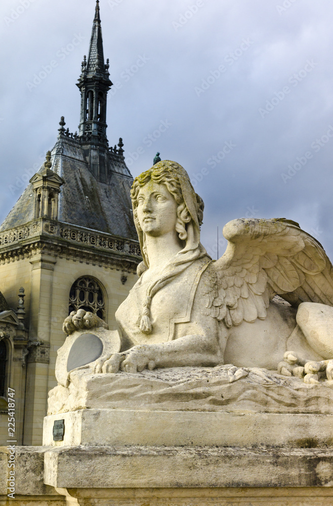 Sphinx statue in front of Palace of Chantilly in golden afternoon light