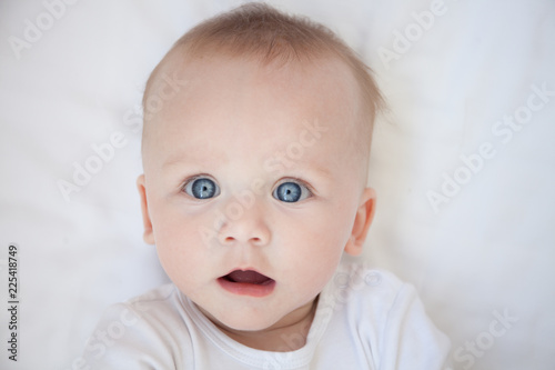 surprised child lies on his back on a white sheet
