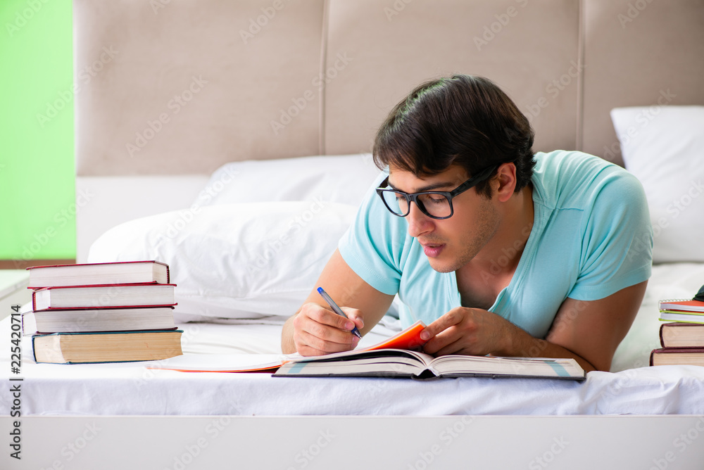 Student preparing for exams at home in bedroom lying on the bed Student preparing for exams at home in bedroom lying on the bed
