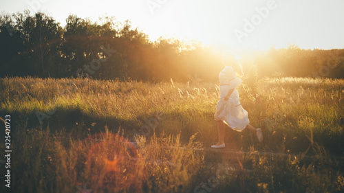 Majestic field in the sunlight. Woman is running on the road