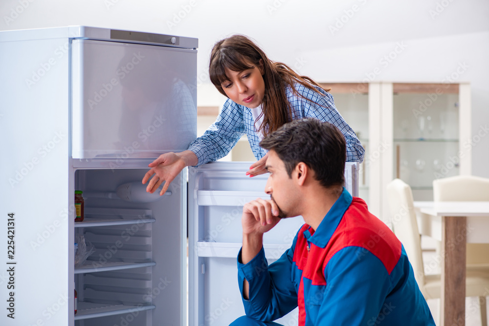 Man repairing fridge with customer Man repairing fridge with customer