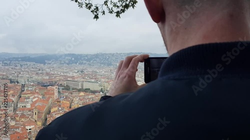 Guy recording on a Samsung on top of a cliff in Nice, France photo