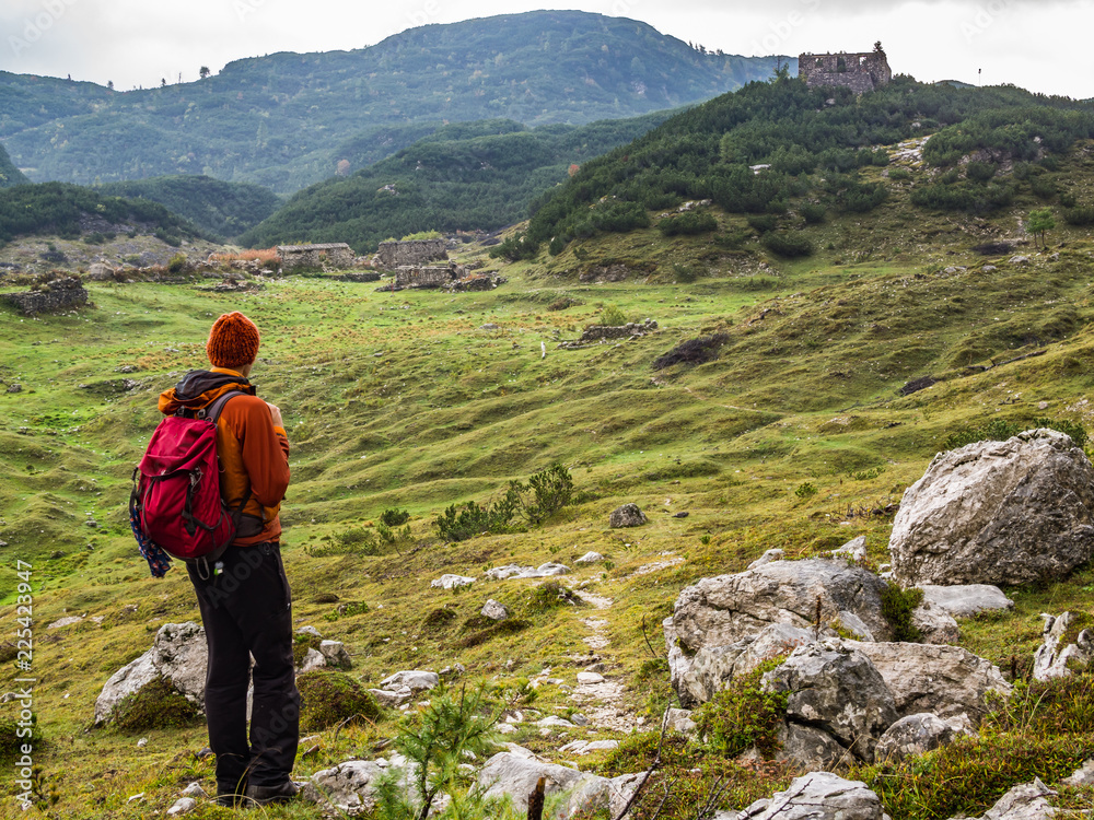 Mountaineer gazing at the ruins of WWI buildings on the Komna mountain plane in Julian Alps, Slovenia