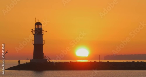 A fisherman next to a lighthouse in Rostock Warnem√ºnde during sunrise photo