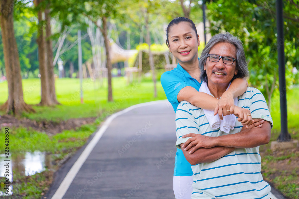 Naklejka premium Portrait of happy. Happy Asian senior couple . They are big hug after Jogging in park. They are smiling and happy in good time , husband and wife, love , Photo concept Health and relax time.