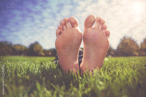 shallow DOF on a man with his  feet crossed in a park on a hot summer day photo
