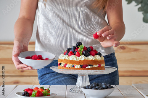 Pastry chef decorates the cake wild berries