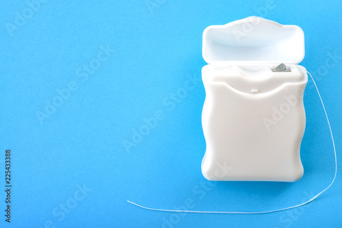 Dental hygiene and oral health concept with a dental floss box isolated on blue background with copy space