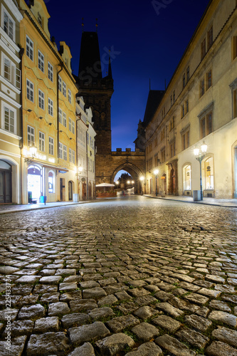 Medieval street leading towards Charles Bridge Tower on a rainy night in Prague