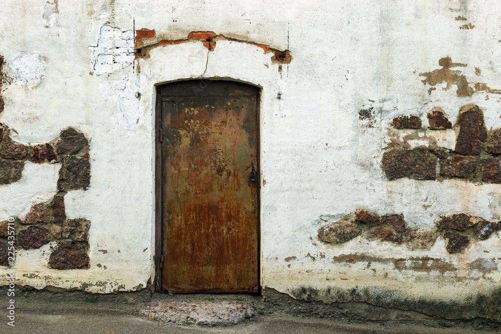 Shabby building facade with closed door. Old white wall. Historical Old building.