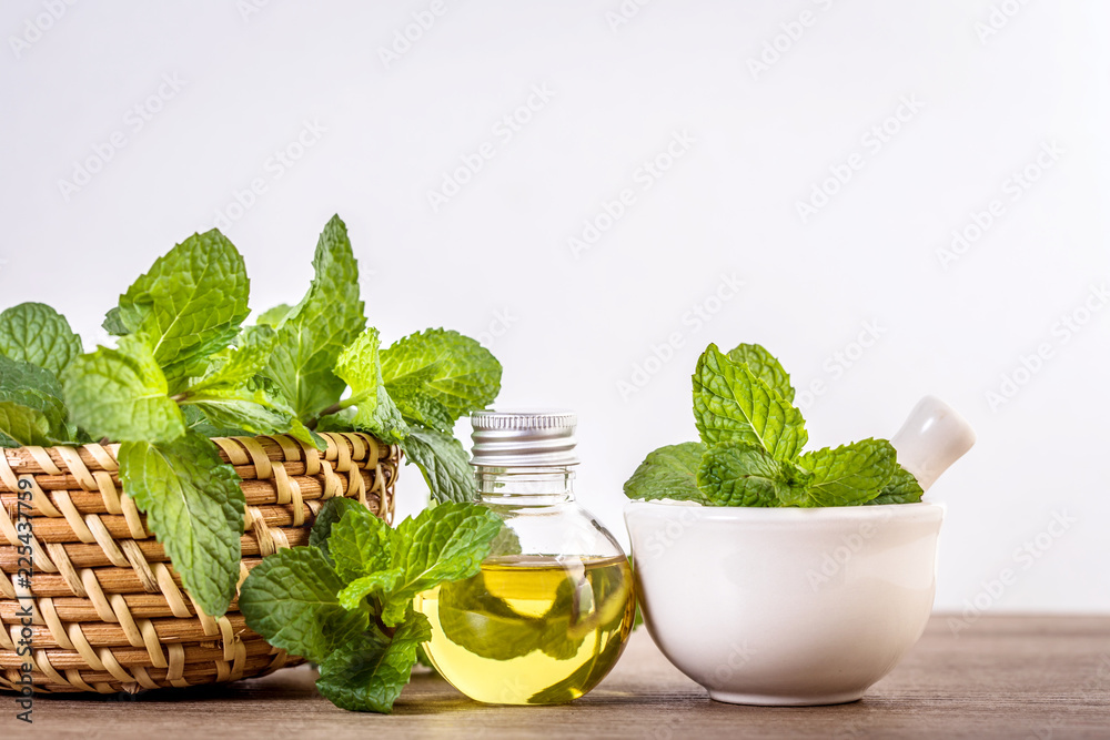 Aroma essential oil from a peppermint in the bottle on the table with fresh green mint leaf - obrazy, fototapety, plakaty 