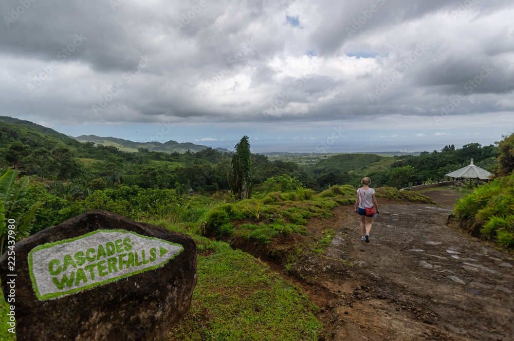 Signpost to cascade waterfalls at the beautiful holiday island Mauritius with a woman walking shot from behind not recognizable.