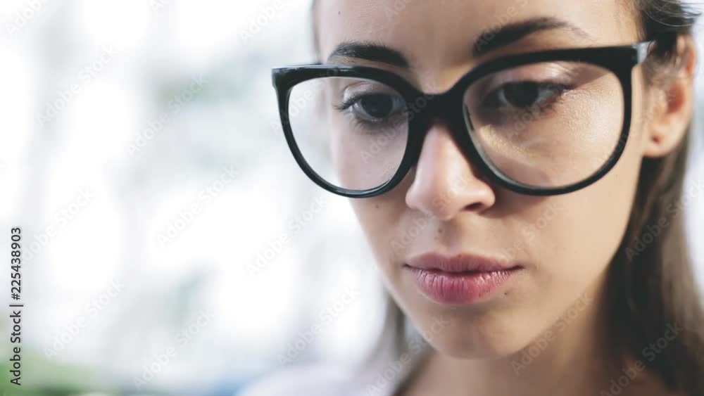 close up portrait of focused young beautiful businesswoman in glasses working on laptop in bright modern office. Business or freelance concept close up portrait of focused young beautiful businesswoman in glasses working on laptop in bright modern office. Business or freelance concept