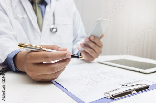 Doctor using laptop and smartphone in office.