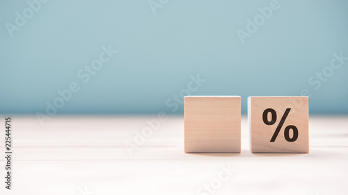 Close up a percentage sign with empty wood cube for text number on blue background, copy space. photo