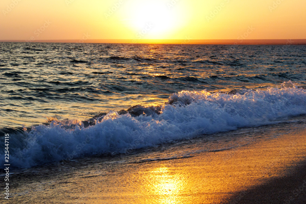 Naklejka premium Sunset on the sea on the beach. Bright yellow sunset. The wave on the beach at sunset. 