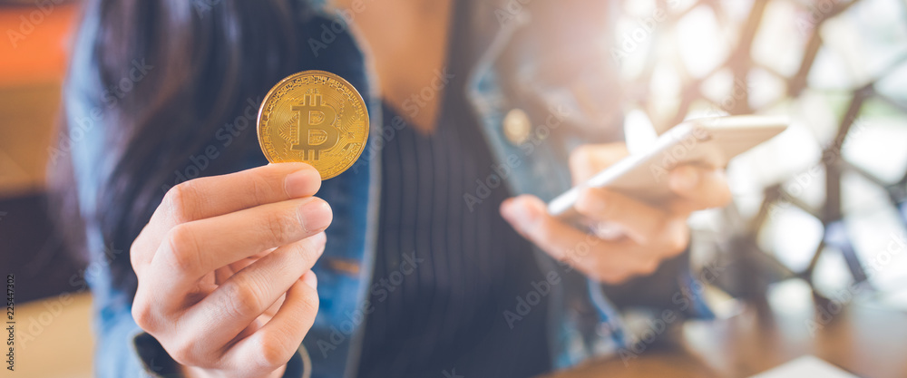 The hand of a woman holding a currency, bitcoin.