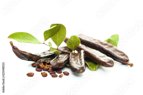 Carob. Healthy organic sweet carob pods with seeds and leaves on white background photo