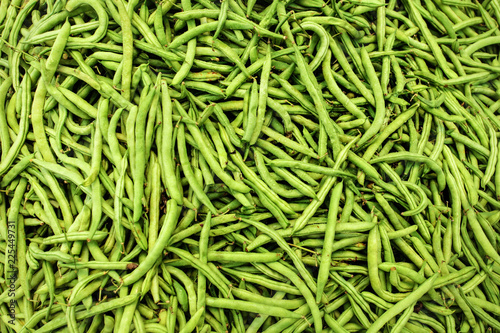 Pile of wet green (string) beans displayed on food market. Abstract healthy nutrition background.
