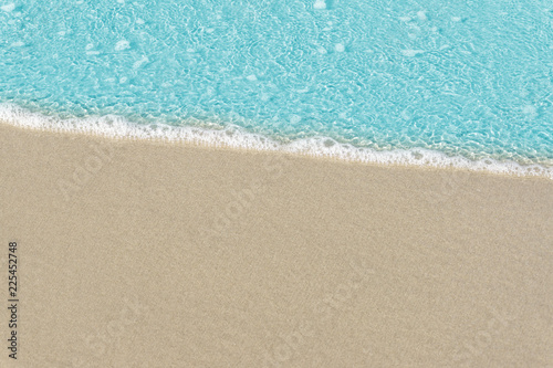 Soft wave of blue ocean on sandy beach. Background / Sand and wave at the beach background. Drop space on bottom for text and other.