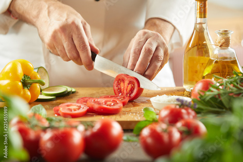 Chef slicing fresh tomatoes for a salad