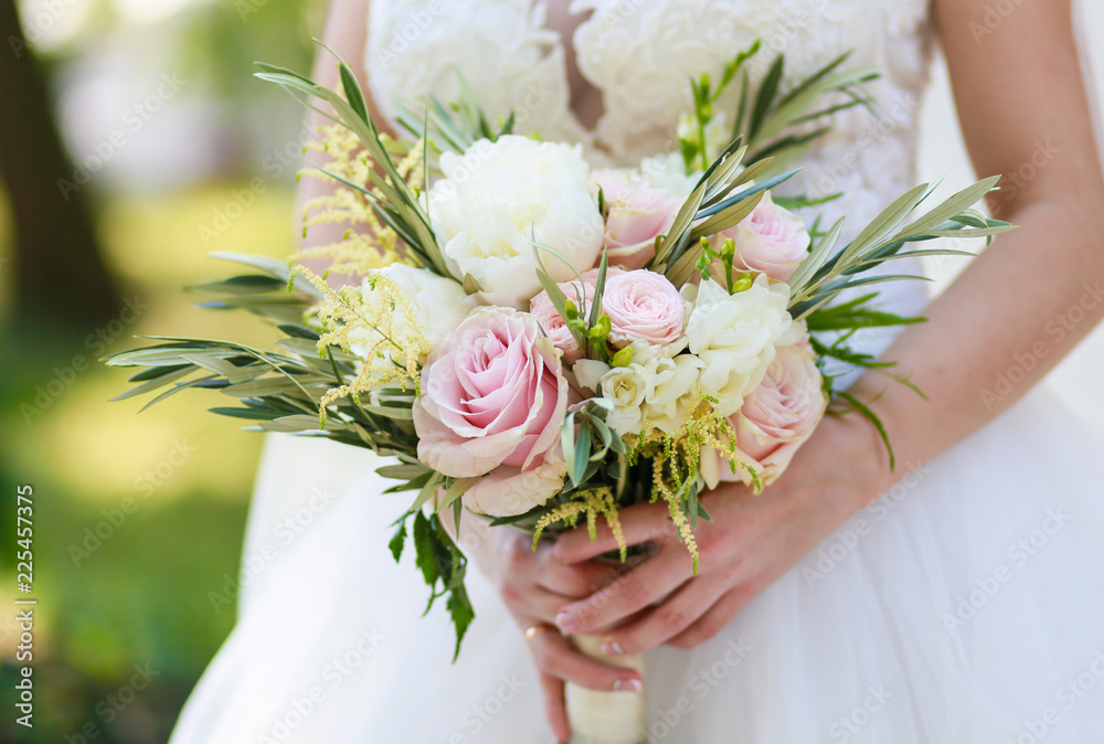 beautiful wedding bouquet in the hands of the bride in nature