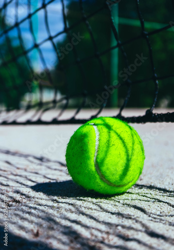 One green tennis ball on court, sport competition concept. Tennis net shadow on the ball. Macro view.