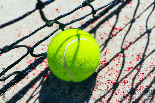 One green tennis ball on court, sport competition concept. Tennis net shadow on the ball. Macro view.