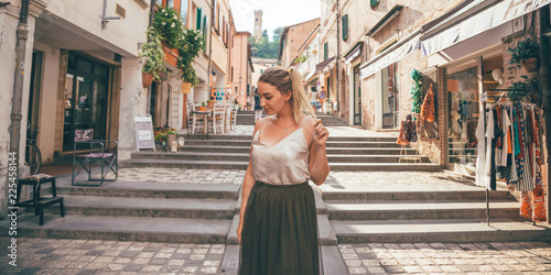 Europe fun, summer happy romantic woman in vacation in Italy, Santarcangelo Di Romagna - portrait of curvy blonde hair woman walking in typical italian old city center - travel and relaxing concept photo