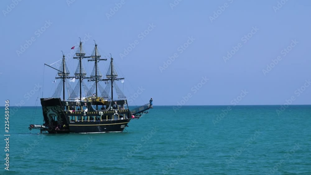 Tourists tour on old style pirate ship on calm clear blue ocean towards the horizon Tourists tour on old style pirate ship on calm clear blue ocean towards the horizon