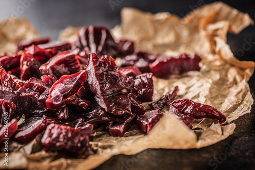 Foto A pile of dried beef jerky pieces on paper and cutting board