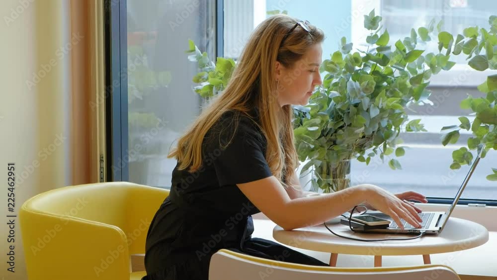 Business woman sitting at a table in a cafe drinking coffee and working on a laptop Business woman sitting at a table in a cafe drinking coffee and working on a laptop