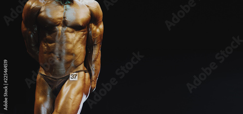 athlete bodybuilder demonstrates abdominal muscles and chest at competitions © Augustas Cetkauskas