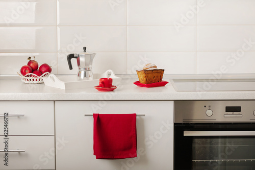 Interior white kitchen with kitchen tools and red crockery.