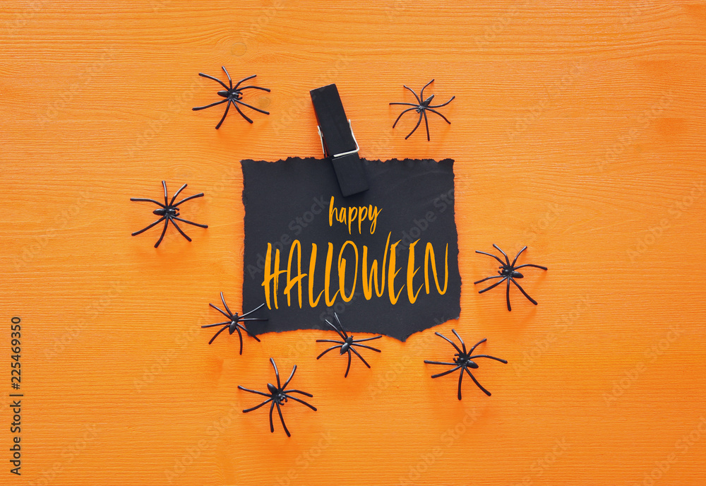 Halloween holiday minimal top view image of letter with text HAPPY HALLOWEEN over wooden orange background. Card and invitation concept.