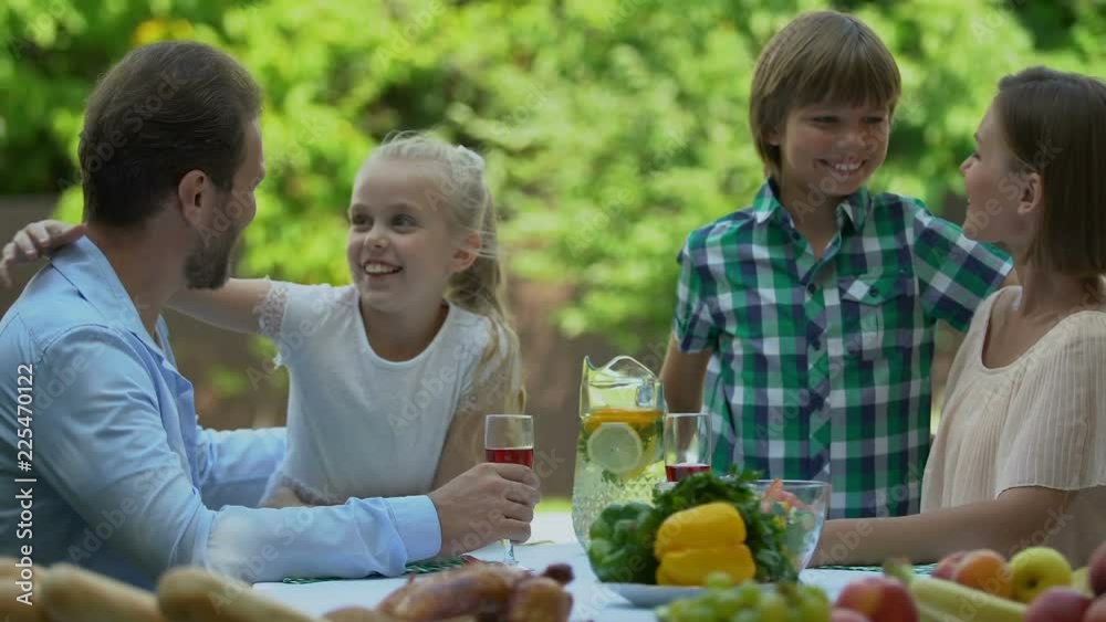 Family having dinner outdoors happy children running to parents and hugging them Family having dinner outdoors happy children running to parents and hugging them