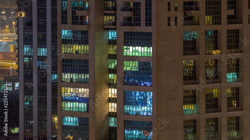 Windows of the multi-storey building of glass and steel lighting inside and moving people within timelapse