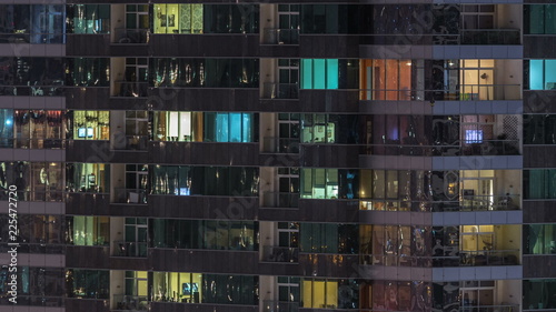 Windows of the multi-storey building of glass and steel lighting inside and moving people within timelapse